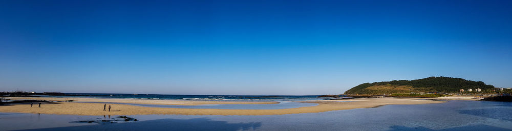 Scenic view of beach against clear blue sky