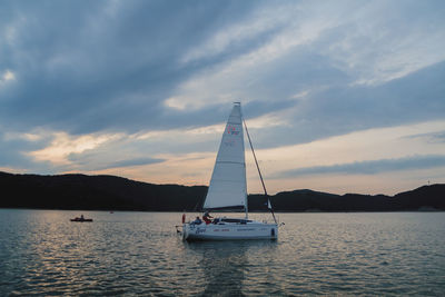 Sailboat sailing on sea against sky during sunset