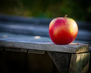 Close-up of apple on table by railing