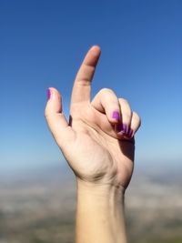 Close-up of human hand against sky
