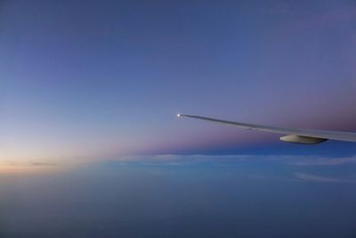 Close-up of airplane flying over sea against clear blue sky