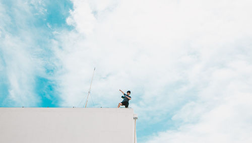 Low angle view of man standing on telephone against sky