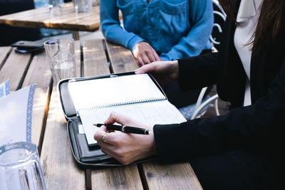 Businesswoman with colleague making notes in diary at restaurant