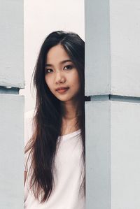 Portrait of young woman against white wall