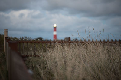 Grass by lighthouse against sky