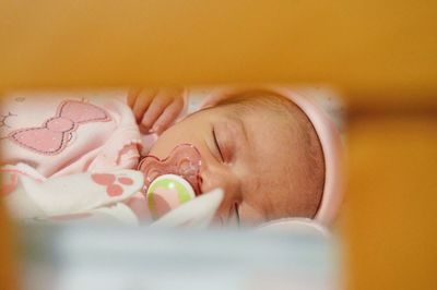 Close-up of newborn baby girl sleeping with nipple at home