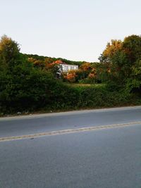 Road by trees against sky