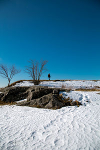 Man on snow covered land against clear blue sky