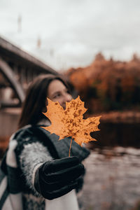 Close-up of woman holding maple leaf during autumn