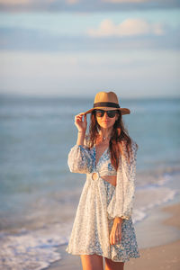 Young woman wearing hat standing at beach