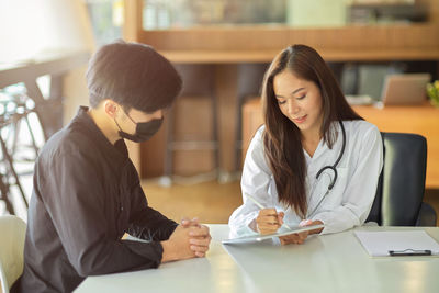 Doctor examining patient wearing mask at clinic