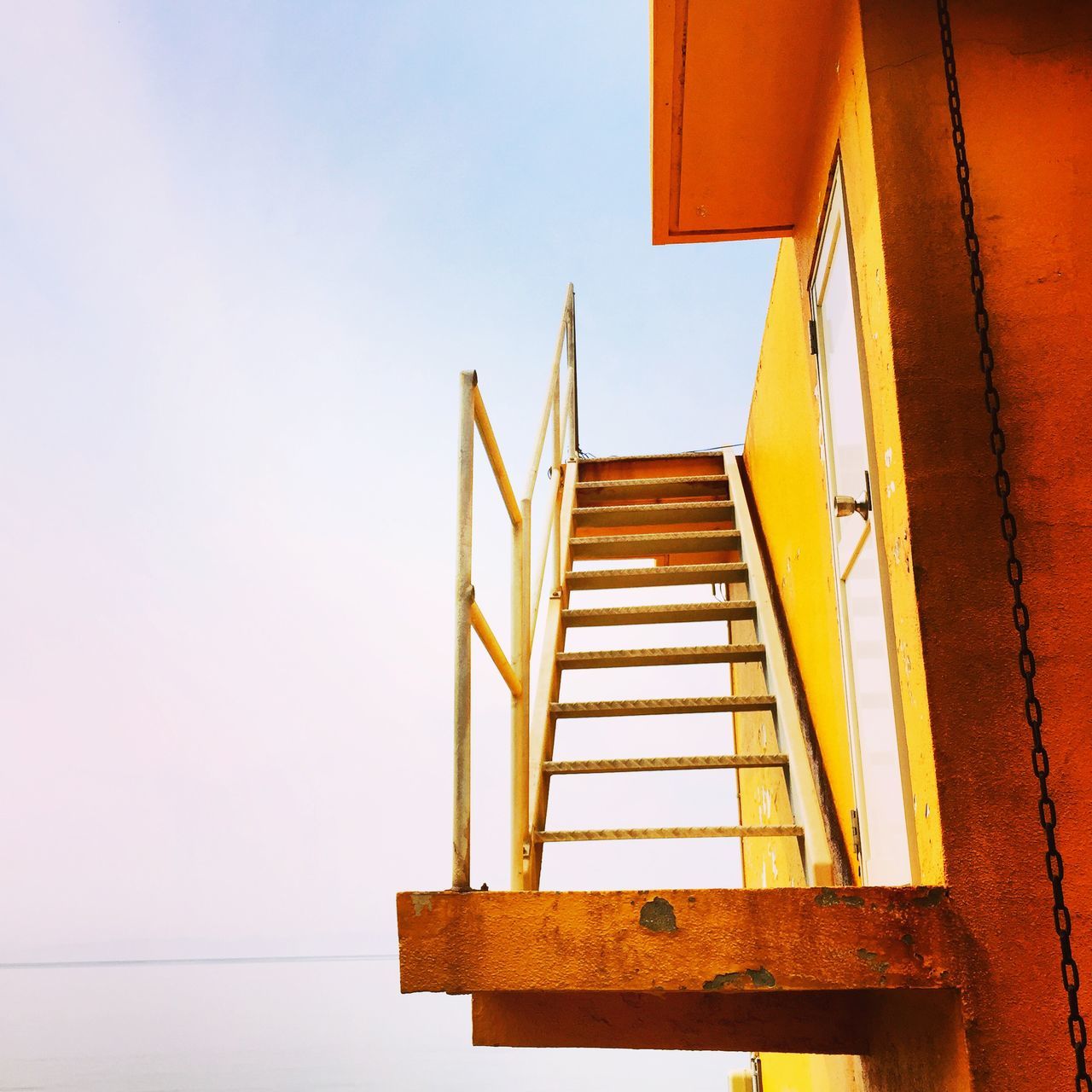 architecture, built structure, low angle view, building exterior, clear sky, building, window, residential structure, residential building, copy space, no people, house, wall - building feature, yellow, day, outdoors, sky, staircase, high section, steps