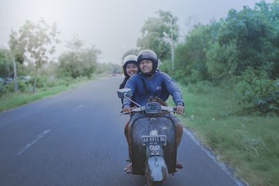Portrait of young man riding motorcycle on road