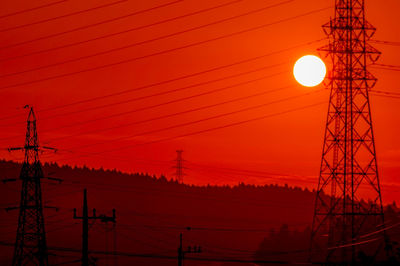 Silhouette of electricity pylon at sunset