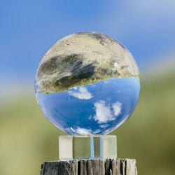Close-up of crystal ball against blue sky