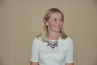 Portrait of a smiling young woman against wall