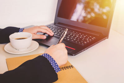 Midsection of woman holding coffee cup on table