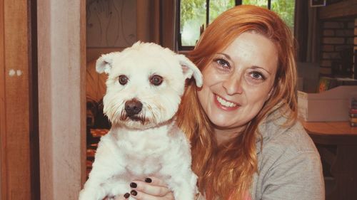 Portrait of mature woman holding dog at home