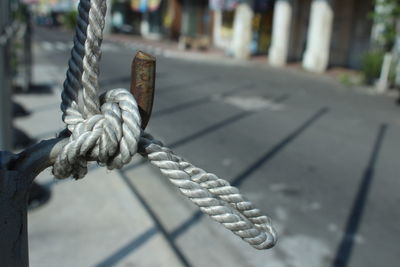 Close-up of rope tied by road on metal