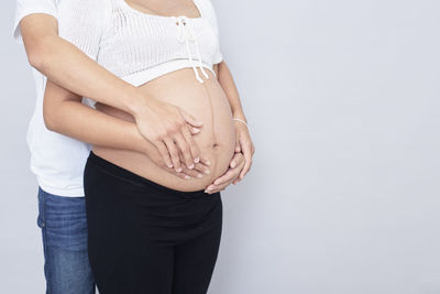 Midsection of woman standing against white background