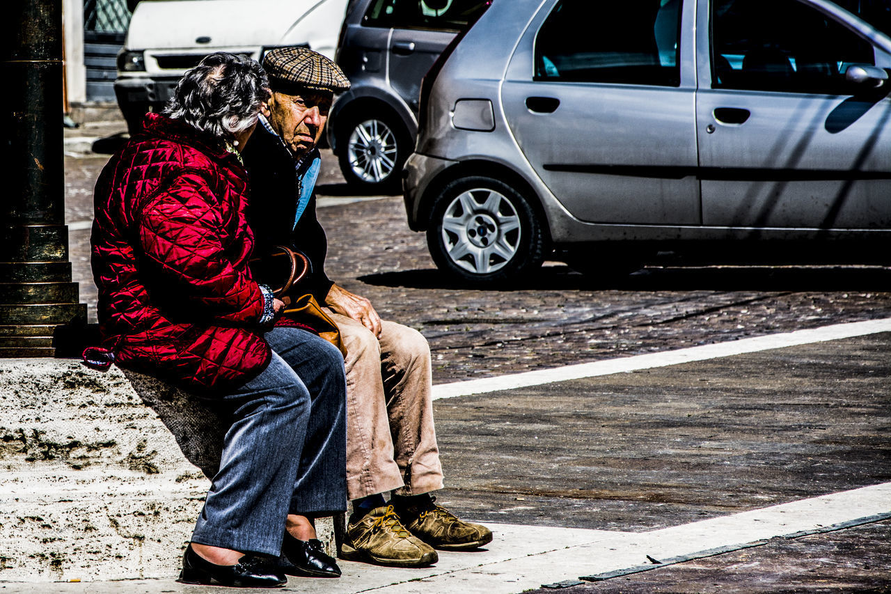 SIDE VIEW OF MAN SITTING ON CAR