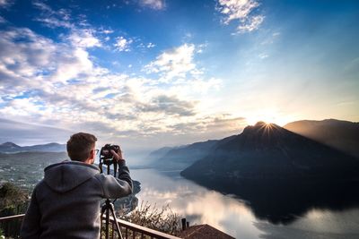 Man photographing mountain against sky