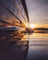 Rowboat moored on lake against sky during sunrise