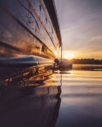 Sailboats moored on sea against sky during sunset