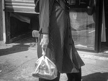 Rear view of woman with umbrella walking in city