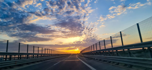 Bridge over road against sky during sunset