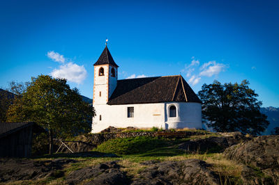 Low angle view of trees and chapel against blue sky