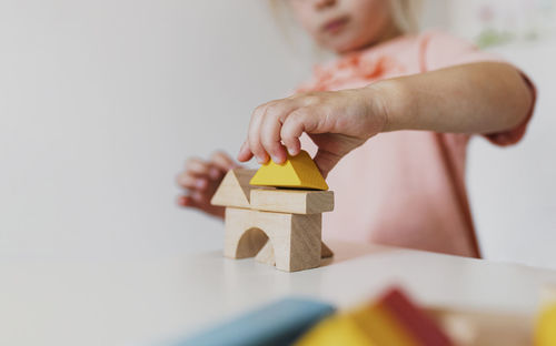 Child girl playing wooden building blocks at home, kindergarten. development, construction concept