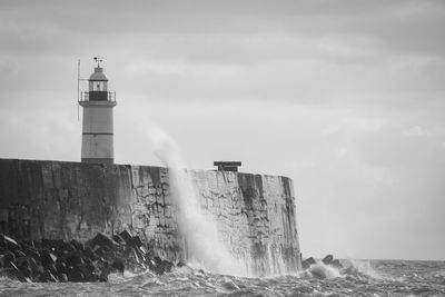 Lighthouse by sea against sky