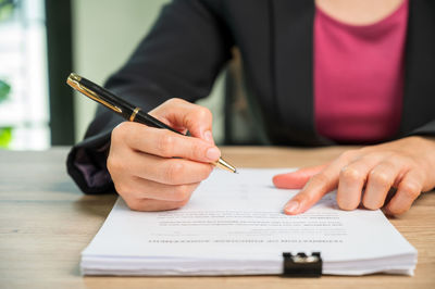 Midsection of man holding paper while sitting on table