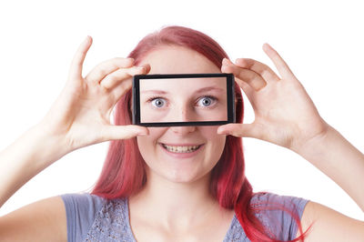 Portrait of smiling woman holding smart phone with eyes image against white background