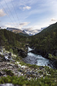 Scenic view of river by mountains against sky