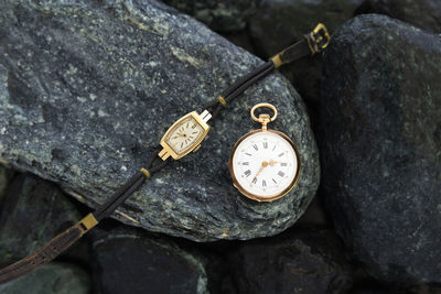Close-up of pocket watch and wristwatch on rock