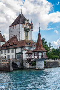 Buildings by river against sky