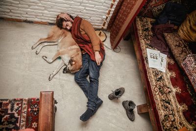 High angle view of young man with dog sleeping on floor