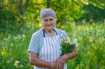 Portrait of young woman standing against plants