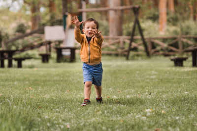 Cute little caucasian boy with blue eyes running on the grass in a park on a sunny day