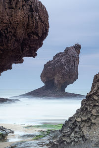 Rock formation on beach against sky