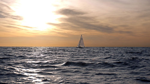 Sailboat sailing on sea against sky during sunset