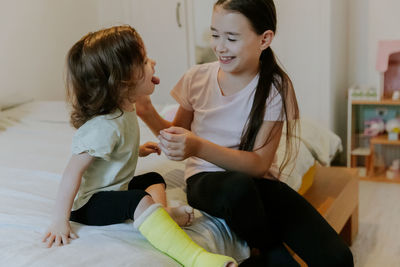 Two girls are fooling around while sitting on the bed in the morning.