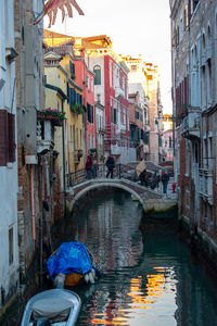 Boats in canal amidst buildings in city during rainy season