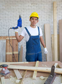 Portrait of carpenter holding drill at workshop