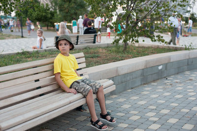 Full length of boy sitting on bench in park