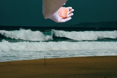 Midsection of person holding sea shore