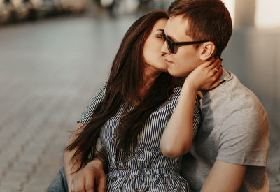 Beautiful woman kissing boyfriend in city during sunset