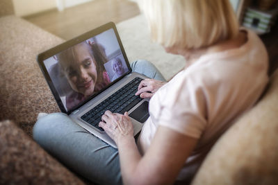 Midsection of woman using laptop at home